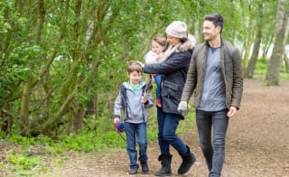 Family of four walking through trees together at Tattershall Lakes. image