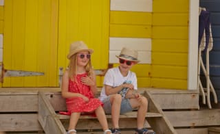 Two children sat on the steps in front of a bright yellow door. image