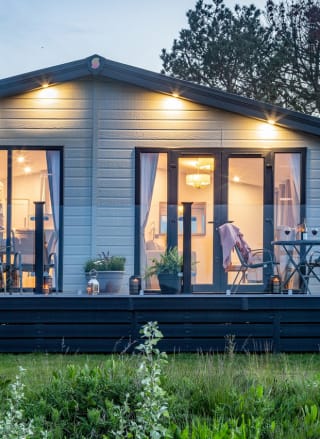 A photo of a static caravan with the patio doors facing the camrea. The photo is taken durng a sunset.