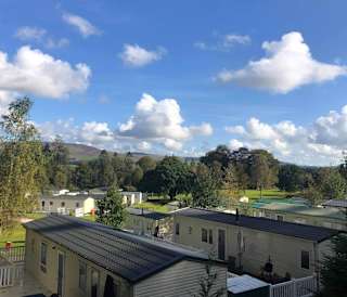 An aerial view above the roofs of holiday caravans in Moffat Manor, with hills in the distance.
