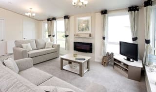 The interior of one of our Luxury holiday lodges. There are two large sofas, a TV, and plenty of space around a coffee table. image