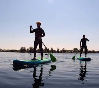 A photo of two people paddle boarding in the calm lake at our Tattershall Lakes holiday park. image