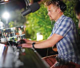 A male performing on a a set of DJ decks.