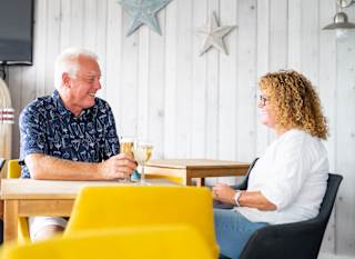 A couple enjoying a drink together at The Muddy Duck Clubhouse at our Essex holiday park, Mersea Island. image