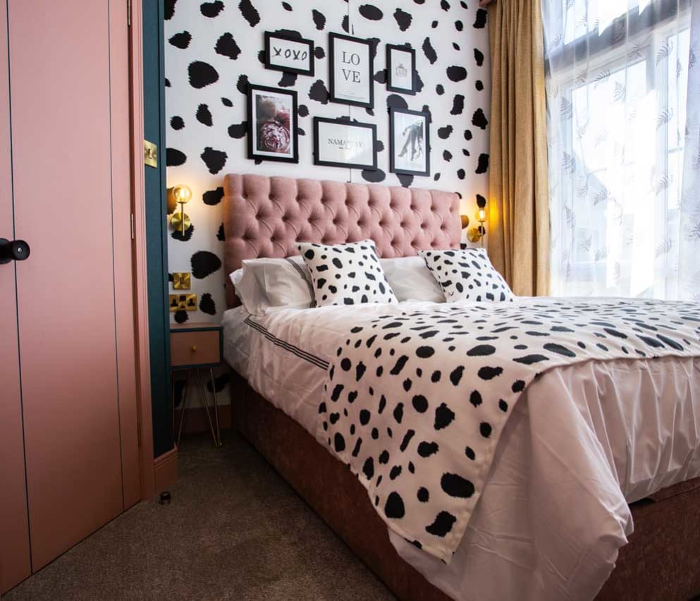 A double bedroom with cow spot print feature wall and continued on the bedding with light pink duvet covers. image