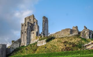 An image of Corfe Castle on a bright day with blue skies. image