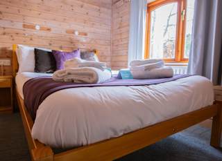 The interior of one of our woodland style holiday lodges. There's a bedroom with a double bed and window. image