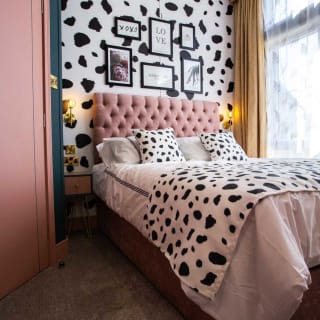 A double bedroom with cow spot print feature wall and continued on the bedding with light pink duvet covers. image
