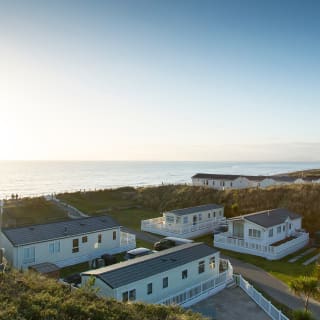 Two rows of caravans with views of the sea and the sun setting at our holiday park in North Wales, Barmouth Bay.