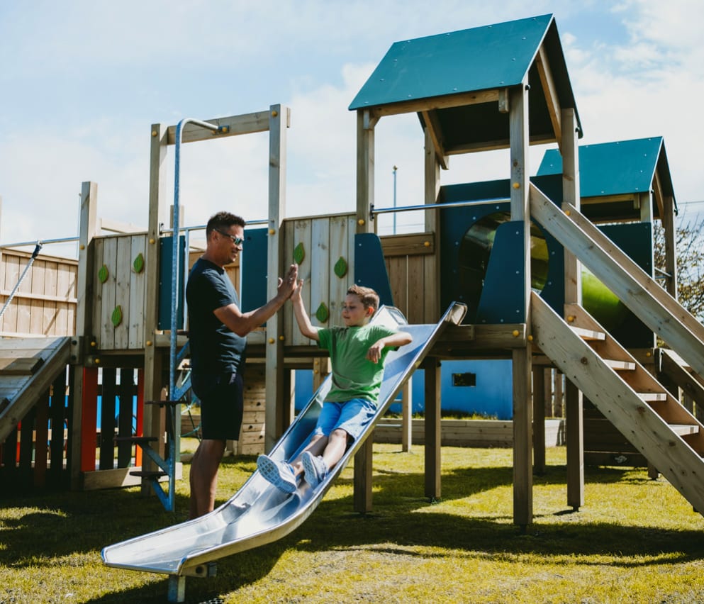 A father and son playing in the outdoor playground at our Bude Holiday Resort, Cornwall.
