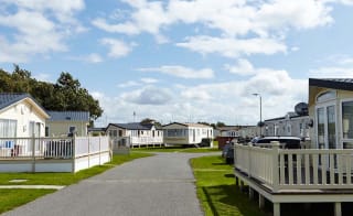 A stone path with holiday caravans seen on either side of the path. image
