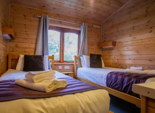 The interior of one of our woodland style holiday lodges. There's a bedroom with twin beds and a double window. image