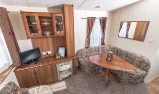 The living and dining area of our budget-friendly value static caravan. The perfect way to stay. image