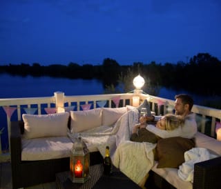 A couple cuddling on the decking of our holiday homes overlooking a lake. image