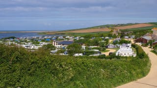 Mobile caravans parked with a wide angle view of the vast countryside and the lagoon located at our East Fleet Farm holiday park in Dorset.
