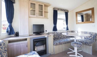 The dining and living area of one of our budget-friendly value static caravans. The perfect way to stay. image