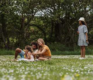 A family enjoying an afternoon together in a field. They are playing a game with a Frisbee.