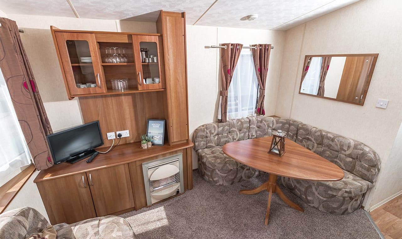 The living and dining area of our budget-friendly value static caravan. The perfect way to stay. image