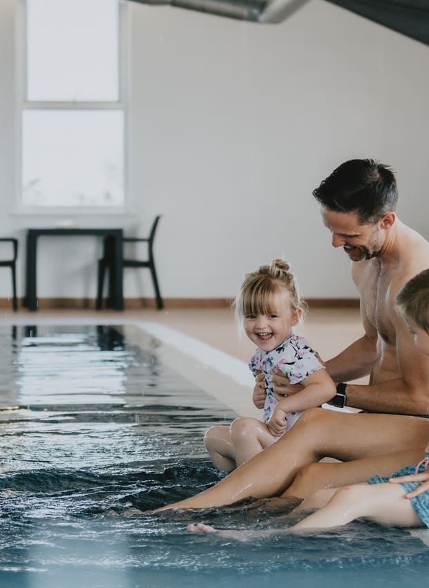 A young family playing in the indoor swimming pool at our holiday resort in Cornwall, Newperran.
