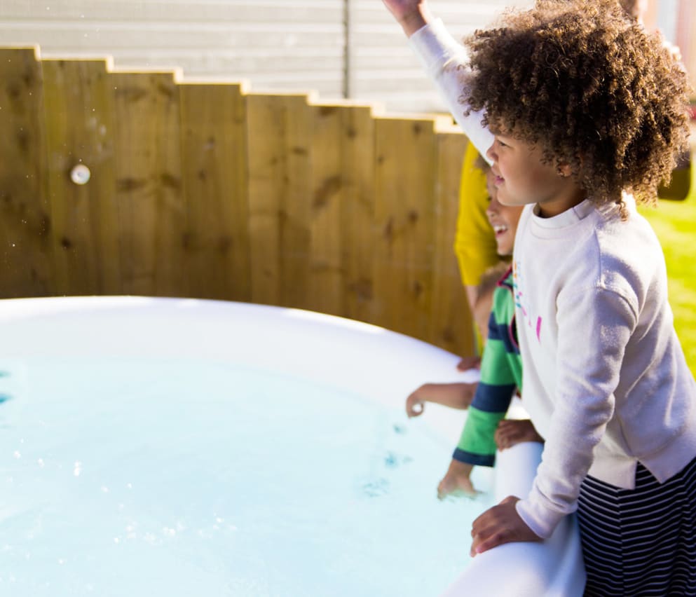 Three young children playing outside one of the hot tubs at our Whitecliff Bay holiday park.