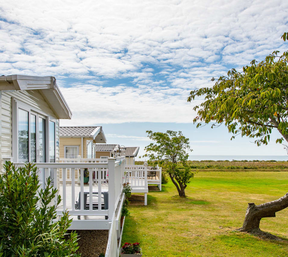 A row of caravans at our park in Essex, Mersea Island, with views of the sea in the background. image