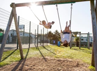 A mother and son on the swings at one of our holiday parks. image