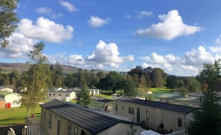 An aerial view above the roofs of holiday caravans in Moffat Manor, with hills in the distance. image