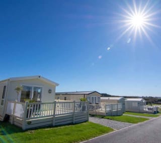 Holiday caravans line down the road, with a big blue sky above and the sun shining brightly. image