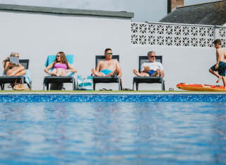 A family enjoying a sunny day at the outdoor heated pool at Bude Holiday Resort. image