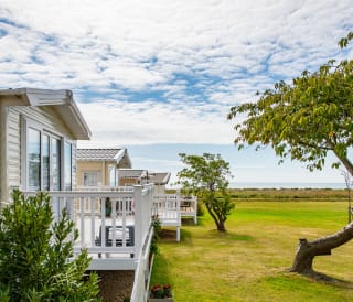 A row of caravans at our park in Essex, Mersea Island, with views of the sea in the background.
