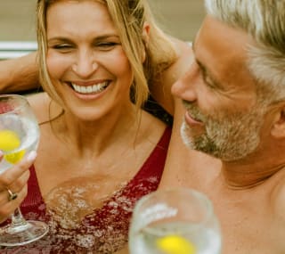 A couple enjoying a drink together in their hot tub. image