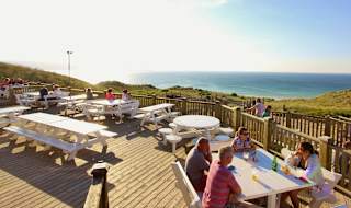 The outdoor eating area of our restaurant at St Ives Bay Holiday Park, with views of the sea.
