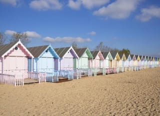 A row of multicoloured beach huts on the beach. image