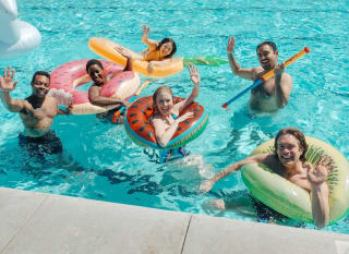 A group of people enjoying a party in a pool. They are on inflatables. image