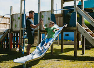 A father and son playing in the outdoor playground at our Bude Holiday Resort, Cornwall. image