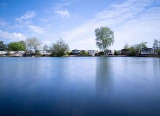 A photo of a riverside horizon during dawn of a row of static caravans. image