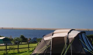 A pitched tent on a bright and sunny day at our East Fleet Farm holiday park in Dorset. image