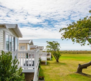 A row of caravans at our park in Essex, Mersea Island, with views of the sea in the background. image