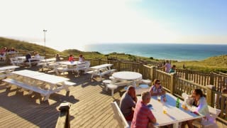 The outdoor eating area of our restaurant at St Ives Bay Holiday Park, with views of the sea.
