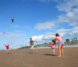 A family of four playing on the beach at our North Wales holiday park, Golden Sands.
