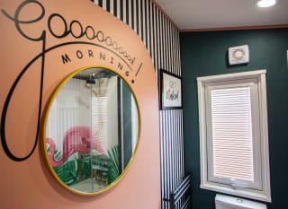 A round wall mounted mirror with the words,'' Good Morning'' painted on. image