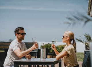 A couple sat outside enjoying a glass of wine together at The Sunset Bar and Eatery, Newperran, on a summers day. image