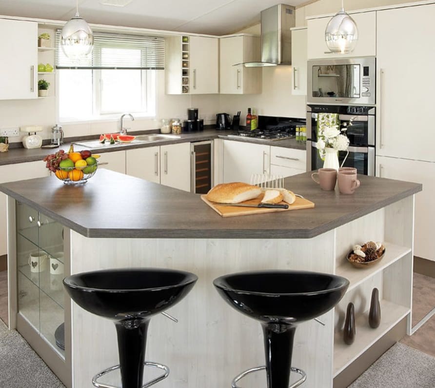 The interior of one of our Luxury holiday lodges. There's a kitchen area with many appliances, and an island in the centre. image