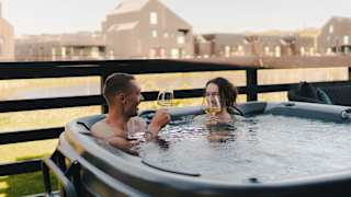 A couple in the hot tub at our stunning Cornish park, Retallack Resort. The male and female are enjoying a glass of wine together.