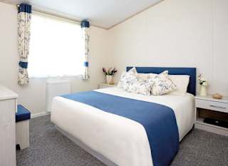 The interior of one of our Luxury holiday lodges. There's a large bedroom with a double bed and window. image