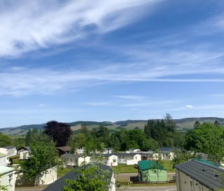 Our Moffat Manor holiday park. There are several luxurious holiday homes onsite, with tall trees and hills in the background.