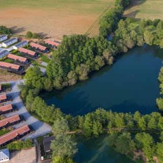 An aerial view of a lake with holiday homes surrounding the lake, with caravans in the distance.