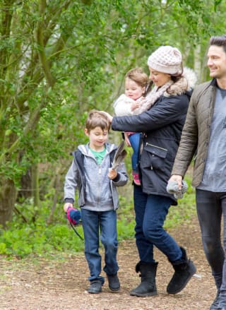 Family of four walking through trees together at Tattershall Lakes.