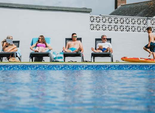 A family enjoying a sunny day at the outdoor heated pool at Bude Holiday Resort.