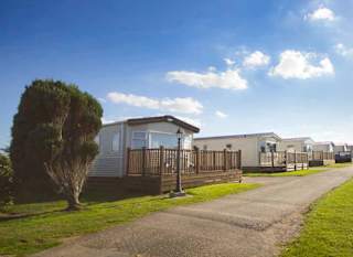 A wide pathway with holiday caravans on either side. Blue skies above. image